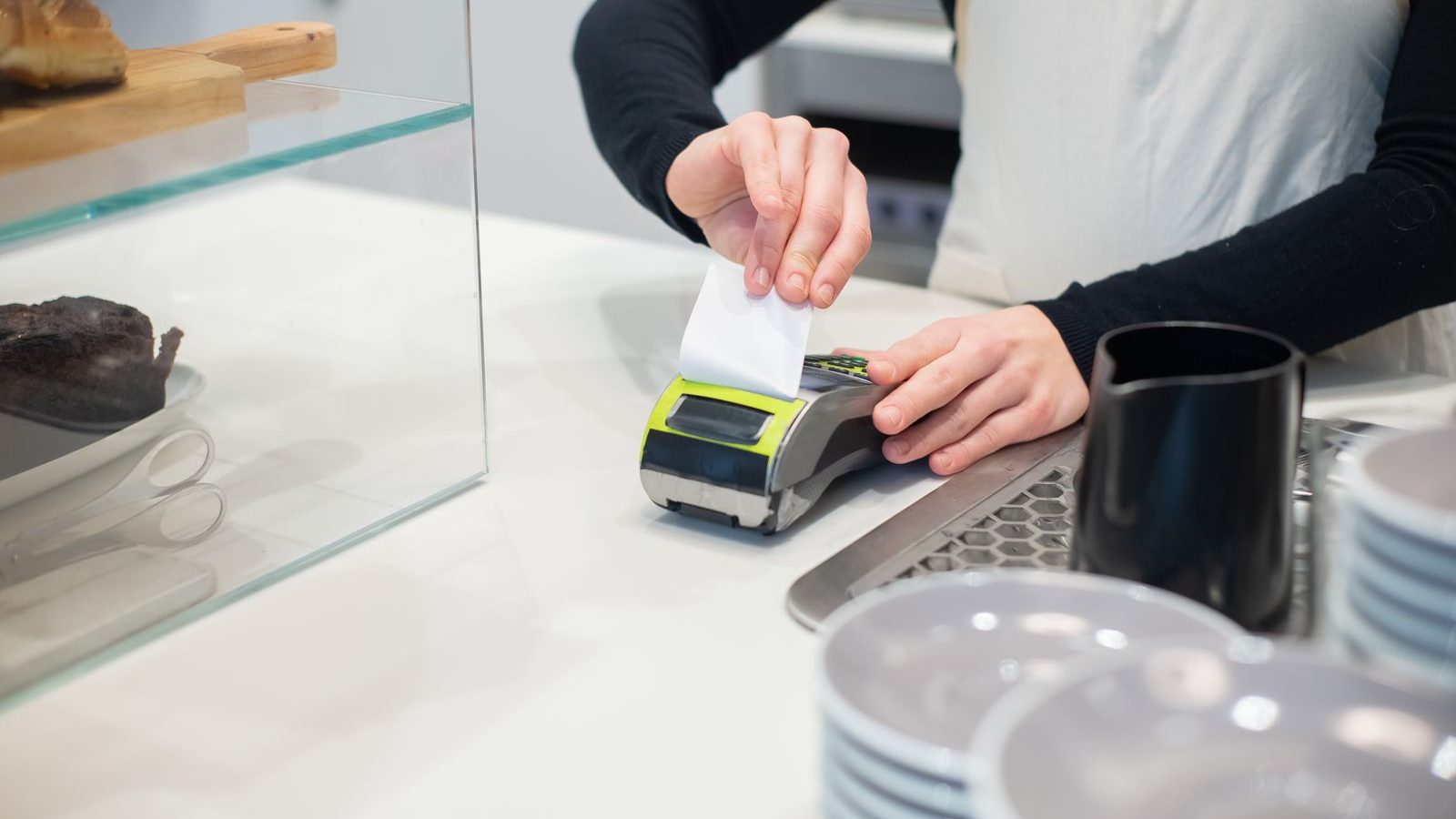 Cafe worker tearing off a card machine receipt at the counter