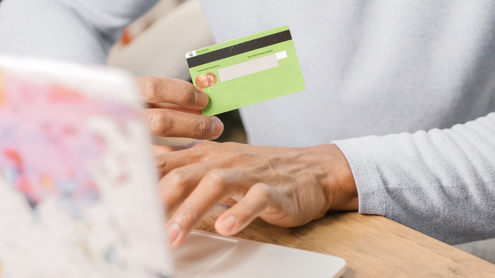 Person holding a payment card while typing on a laptop