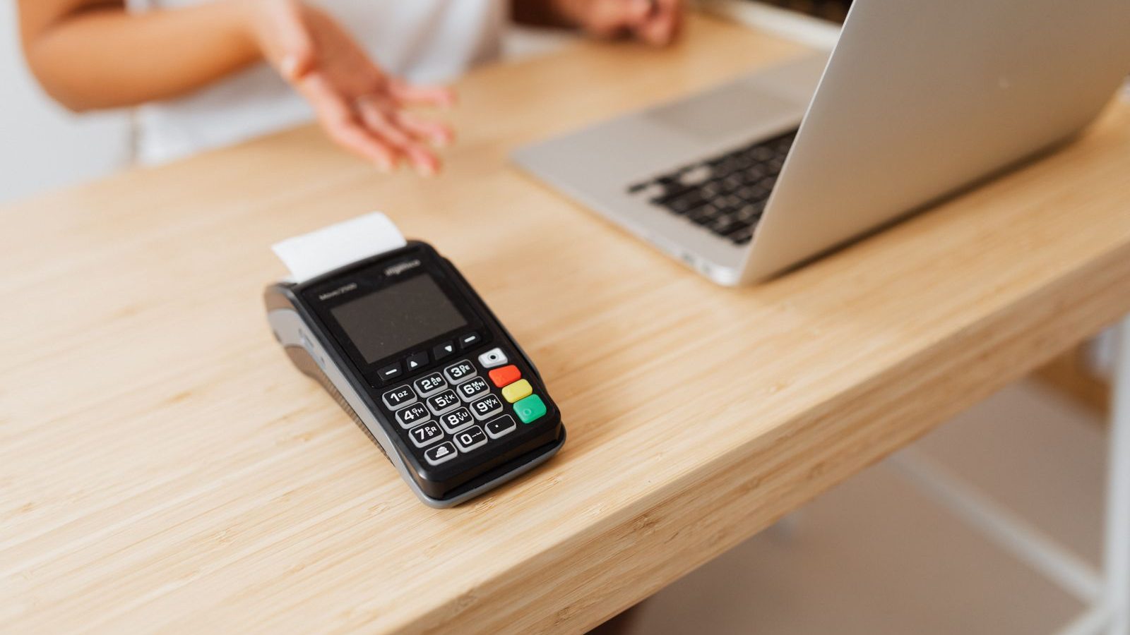 Card machine on a wooden counter next to a laptop